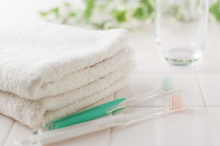 Toothbrush, glass and towels on white tileの写真素材
