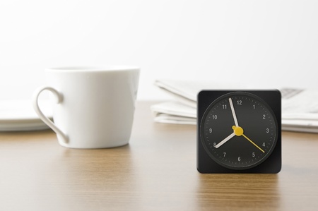 Desk clock and cup and newspaper
