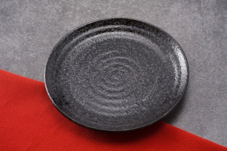 Pottery dish on cloth and stone background, close-up 
