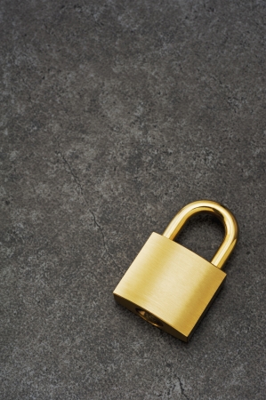 Gold padlock on dark stone surface, background image の写真素材