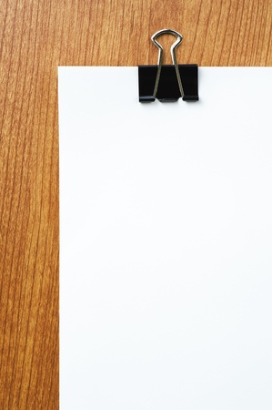 Black clip and blank paper on wooden desk の写真素材