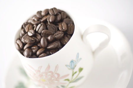 Cup with coffee beans on white background 