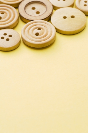 Several wooden sewing buttons on yellow backgroundの写真素材