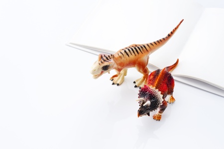 Dinosaur toy and open book on white background の写真素材