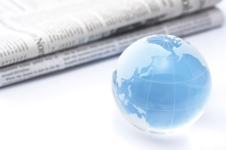 Glass globe and newspaper on white background の写真素材