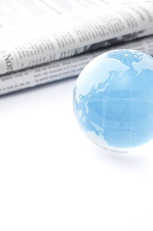 Glass globe and newspaper on white background の写真素材