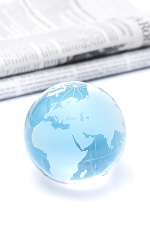 Glass globe and newspaper on white background の写真素材