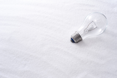 Clear glass incandescent lamp on snow backgroundの写真素材