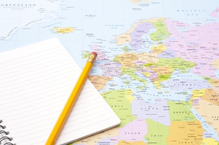 blank notebook and pencil on world map backgroundの写真素材