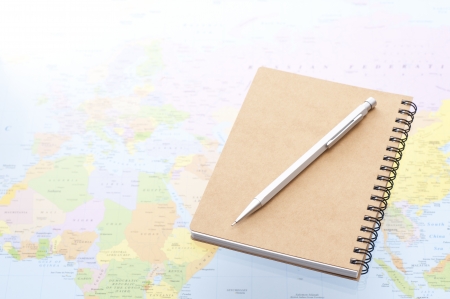 notebook and pencil on world map backgroundの写真素材