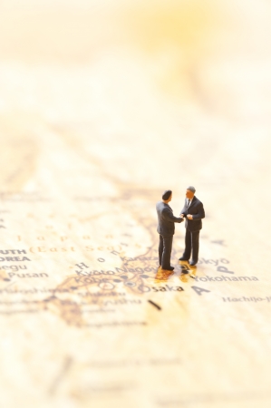 miniature businessman figurines on world map backgroundの写真素材
