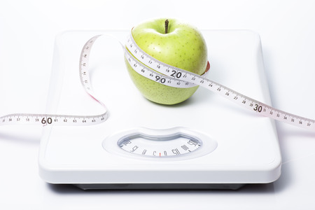 Green apple and tape measure on Bathroom scaleの写真素材