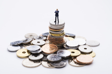 The doll business man on top of the stacked coinsの写真素材