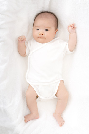 Baby on white sheetsの写真素材