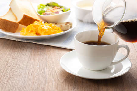 Pouring coffee in a cup for breakfast