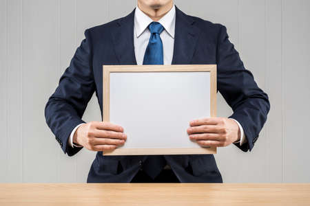 Businessman holding a whiteboard in hand.の写真素材