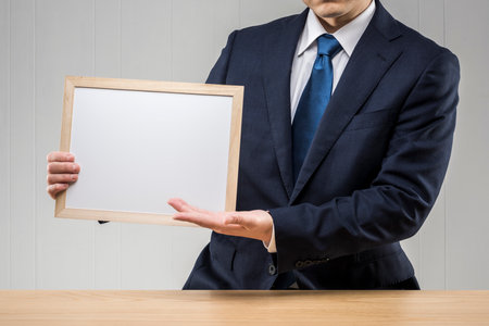 Businessman holding a whiteboard in hand.の写真素材