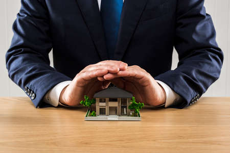Businessman and house model on table.の写真素材