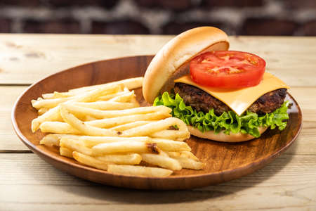 Hamburger and french fries on wood table.