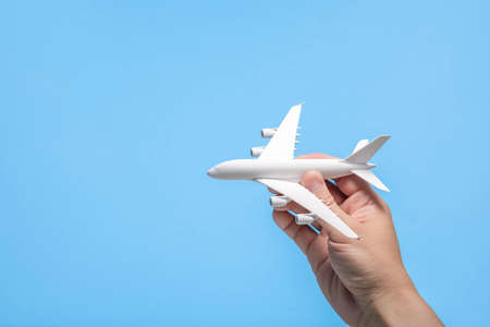 Hand holding airplane model on light blue background.の写真素材