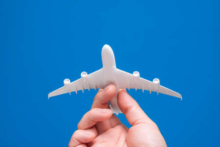 Hand holding airplane model on blue background.の写真素材