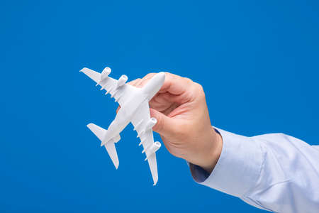 Hand holding airplane model on blue background.の写真素材