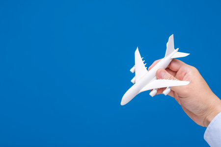 Hand holding airplane model on blue background.の写真素材