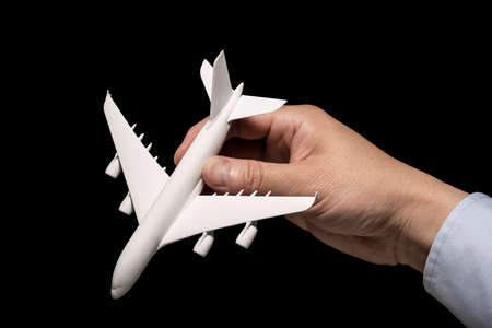 Hand holding airplane model on black background.