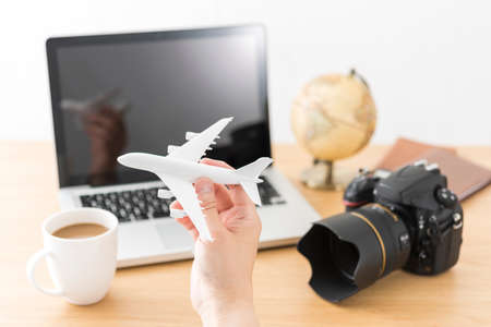 Laptop and airplane model, travel planning.