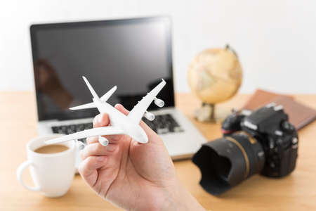 Laptop and airplane model, travel planning.