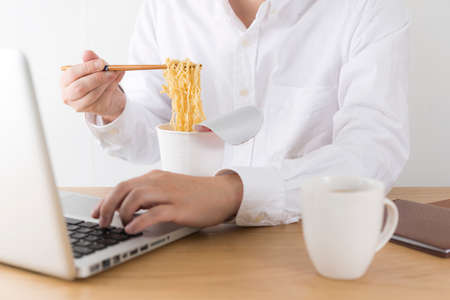 Men eating instant noodles in the office.の写真素材