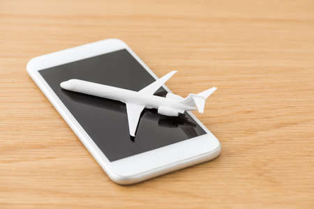 Smartphone and airplane model placed on the desk.の写真素材