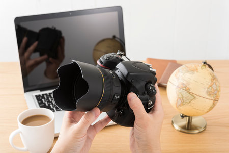 DSLR camera and laptop on wooden desk.の写真素材