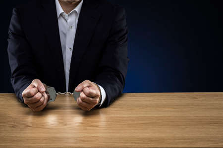 Handcuffed men, wearing a suit.