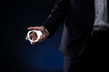 Handcuffed men, wearing a suit.