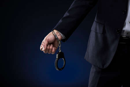 Handcuffed men, wearing a suit.