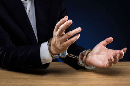 Handcuffed men, wearing a suit.の写真素材