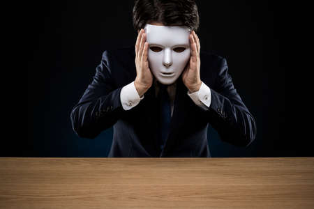 Masked businessman trouble and suffering. dark background.の写真素材