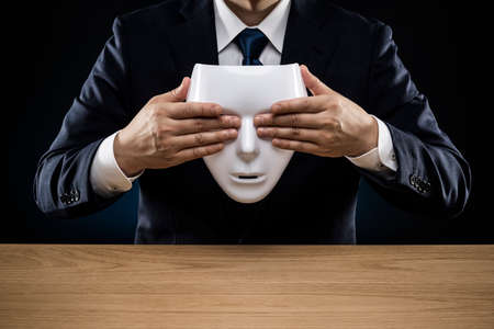 Masked businessman trouble and suffering. dark background.の写真素材