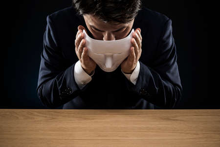 Masked businessman trouble and suffering. dark background.