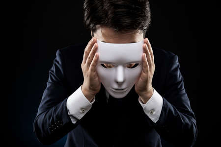 Masked businessman trouble and suffering. dark background.の写真素材