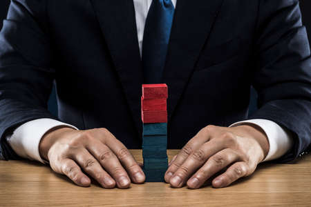 Businessman stacking red and blue blocks.の写真素材