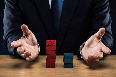 Businessman stacking red and blue blocks.