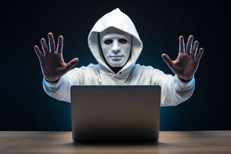 Mysterious man wearing a mask. Open laptop.