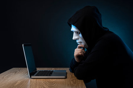 Masked man gaining unauthorized access to computer.