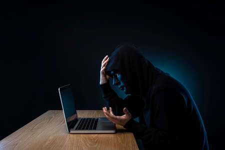 Masked man gaining unauthorized access to computer.