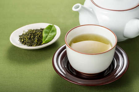 Green tea and tea leaves on a tablecloth.の写真素材