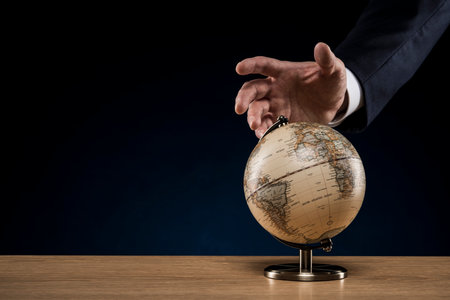 World globe on wooden desk. Businessman hand.