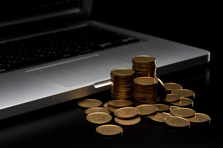 Lots of coins and laptop. Black background.の写真素材