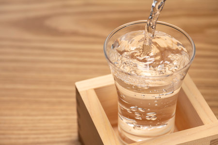 Sake overflows from the square cupの写真素材